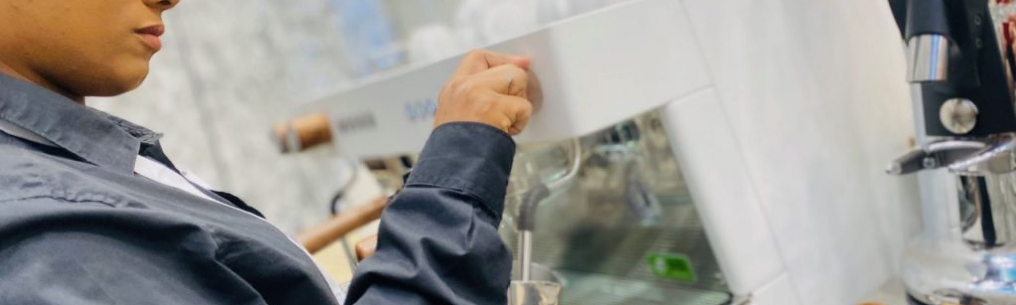 Eine Barista schäumt Milch an einer Kaffeemaschine auf.